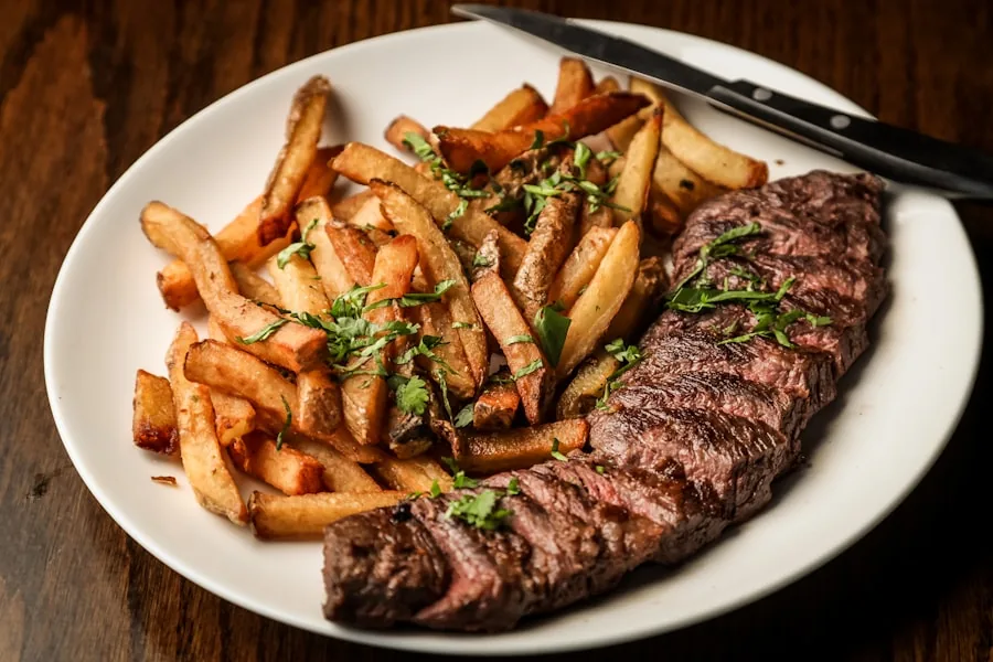 A grilled steak with thick-cut chips and chopped parsley on a white plate